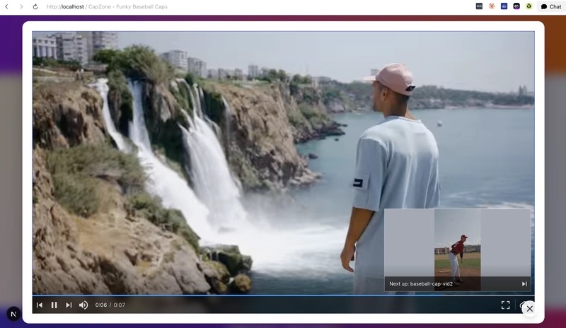 Video player screen depicts a man wearing a cap and overlooking a cliff by the ocean.