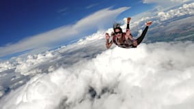A woman skydiving above the clouds.
